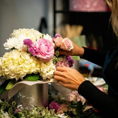 a woman arranging flowers in a vase on a table